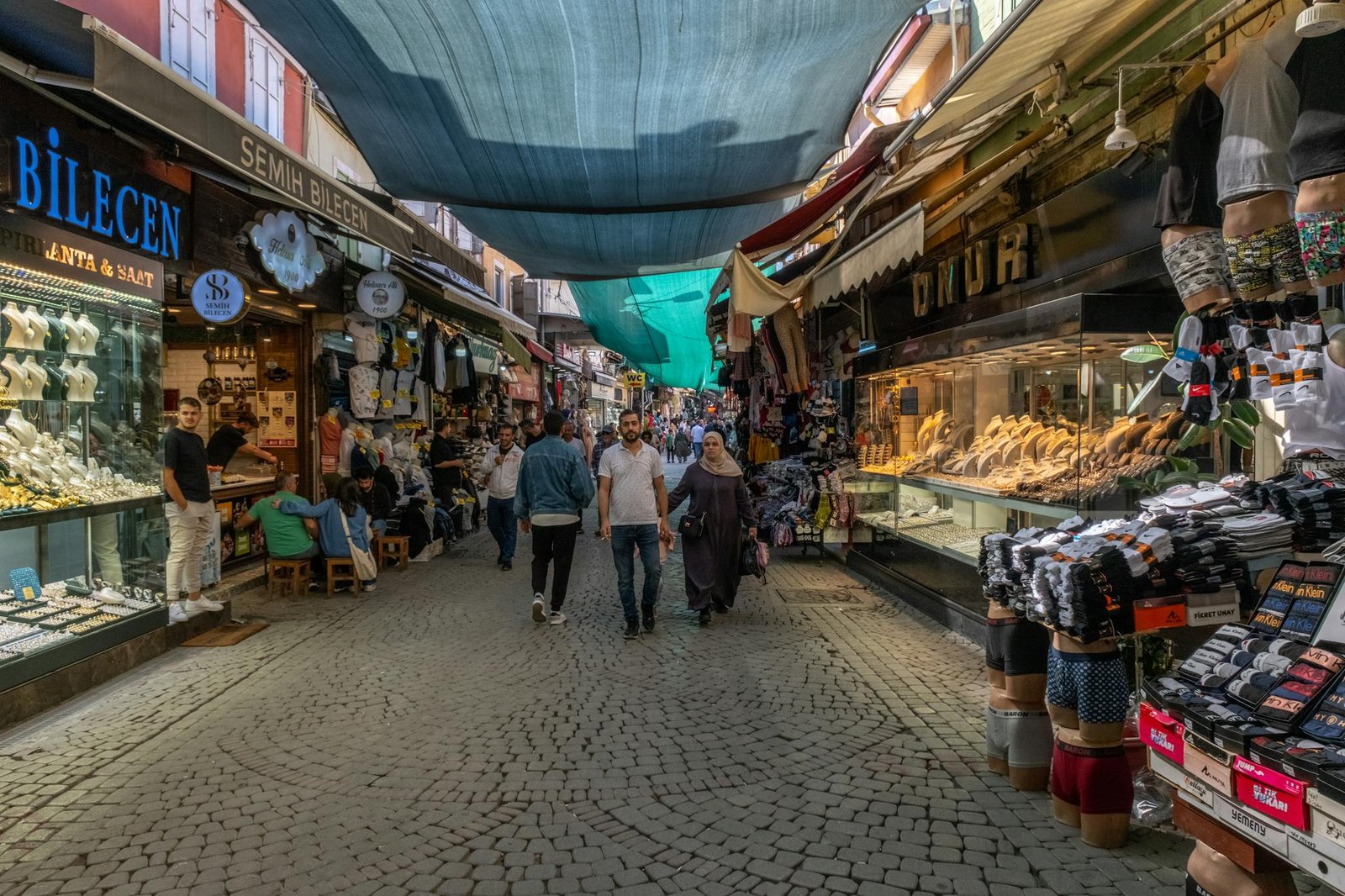 Vibrant market street scene in İzmir, Türkiye, showcasing diverse shops and pedestrians.